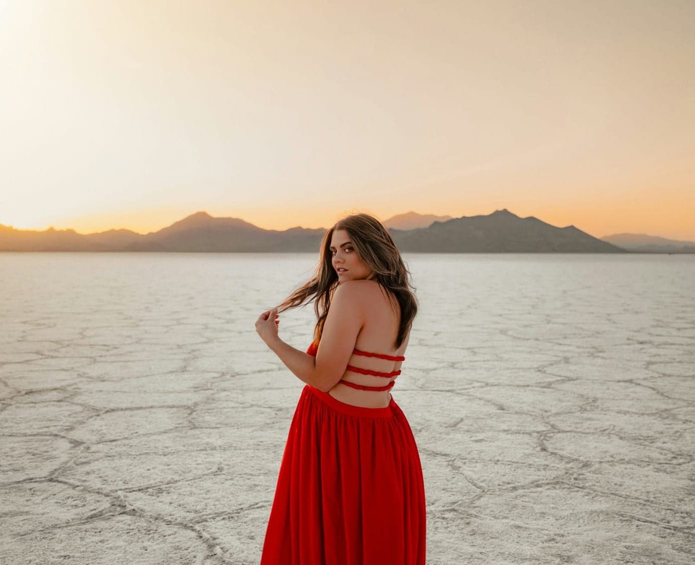 Woman in a red dress on salt flats at sunset