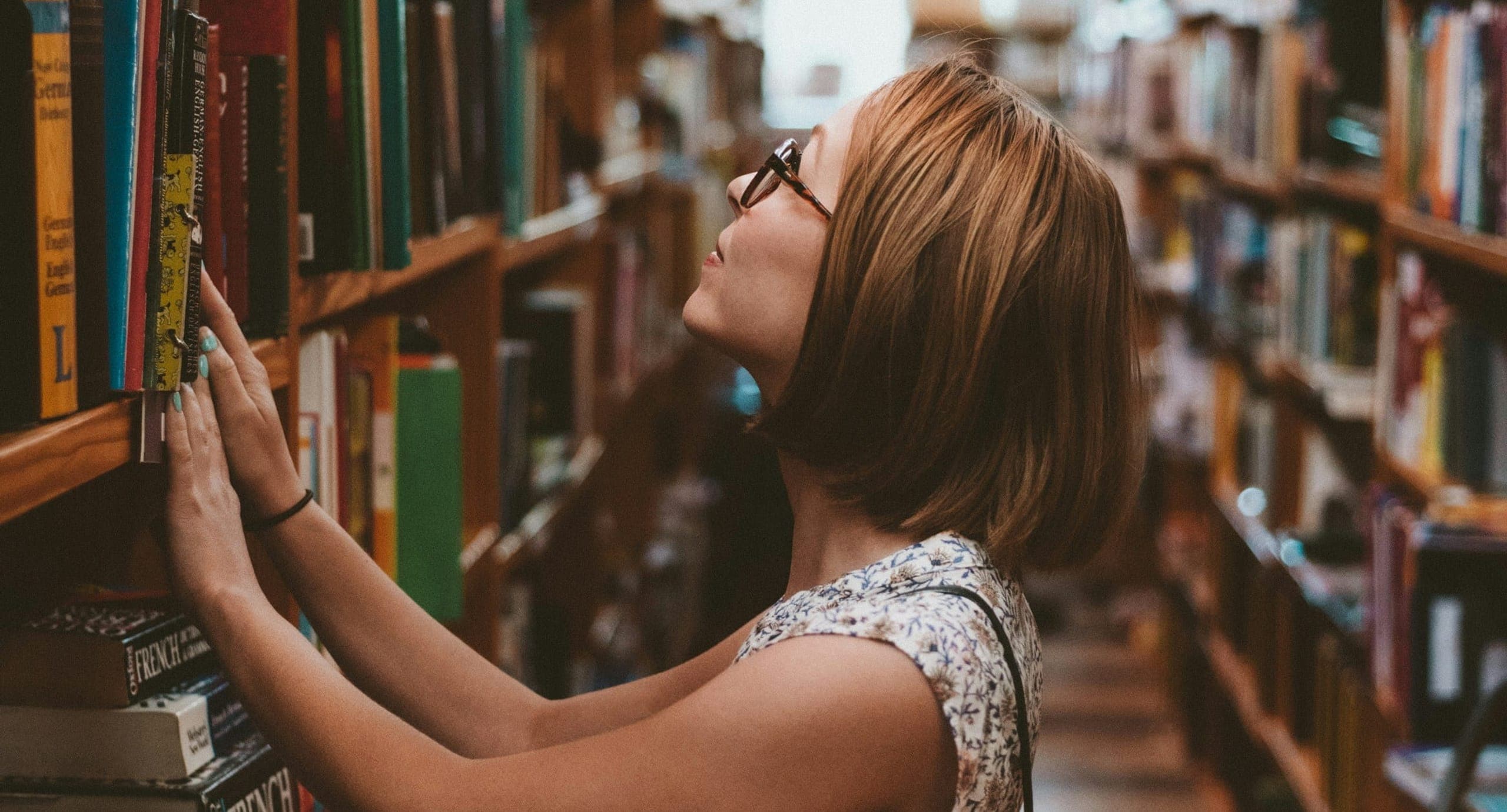Woman looking at books between library shelves