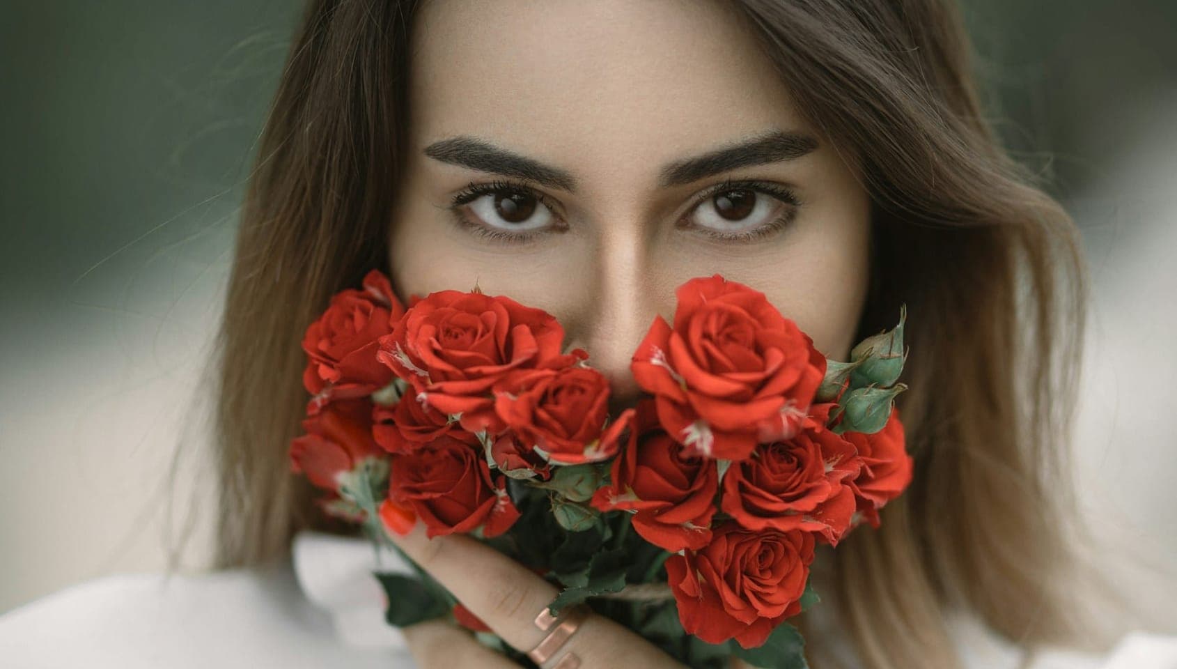 Woman holding red roses in front of her face