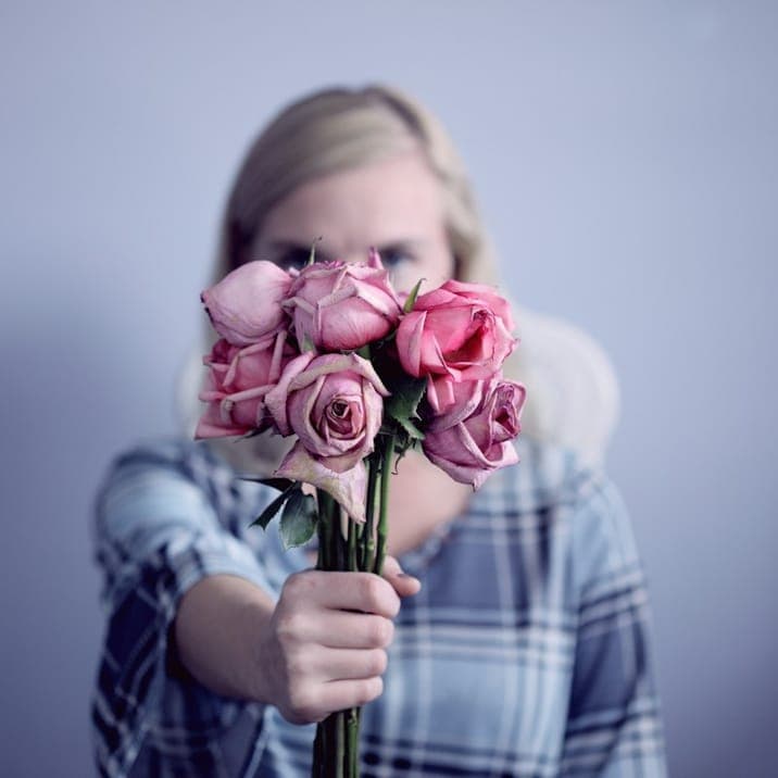 Woman holding pink roses in front of her face
