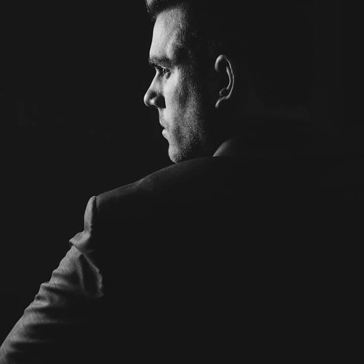 Man in a dark suit in low light